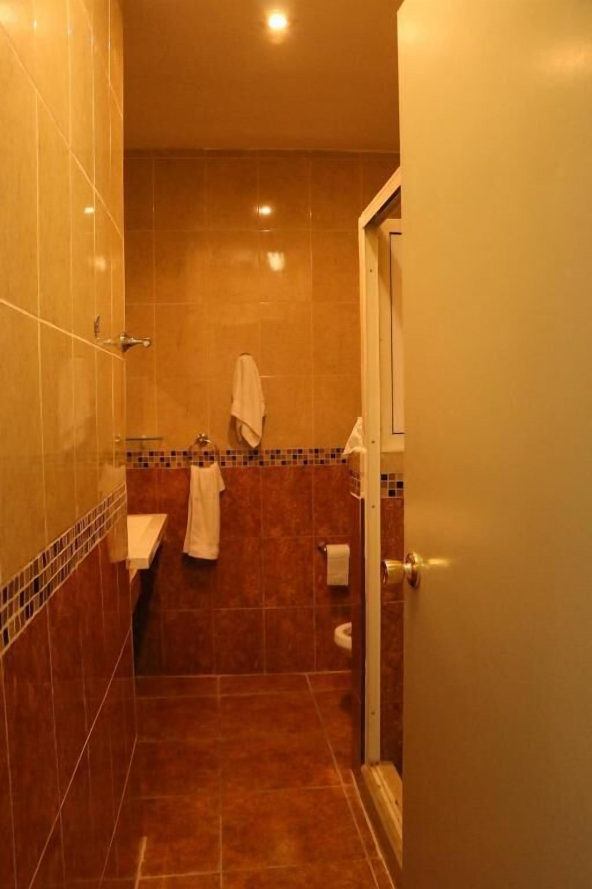 A bathroom with a tiled floor, a sink, a toilet, and a towel hanging on the wall.