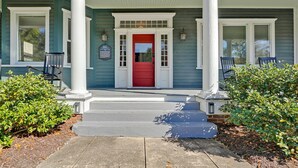 A house with a red door, white columns, and a porch with steps leading up to it. - Savannah Suite on Front (Wilmington)