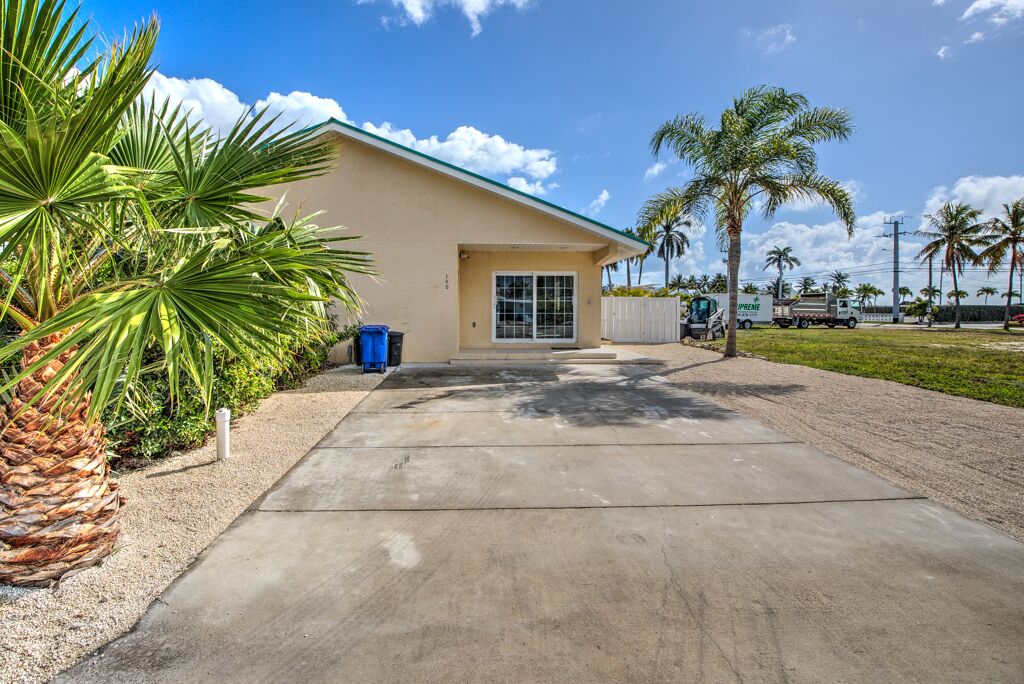 A building with a beige exterior, a glass door entrance, and a concrete driveway.