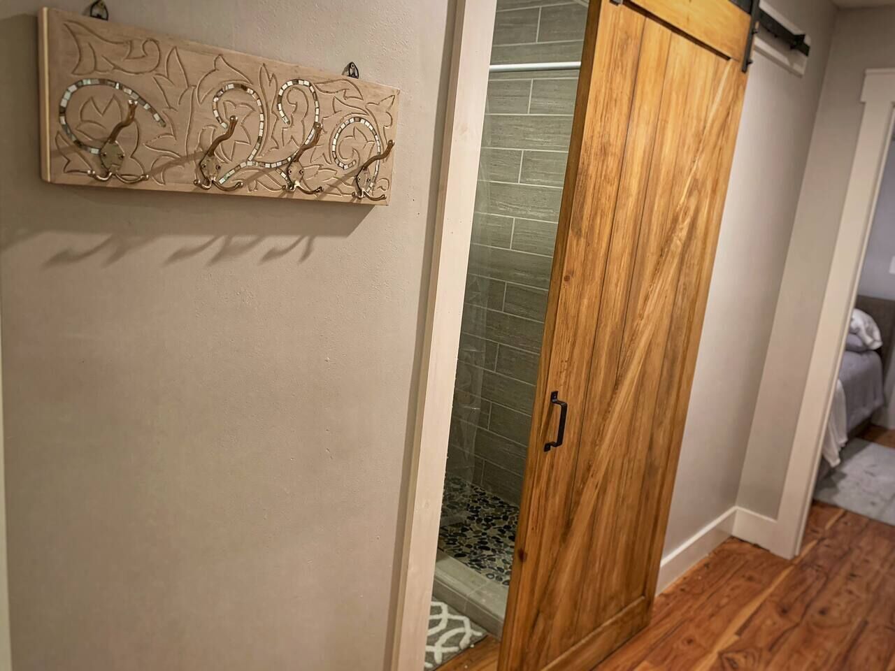 Ein Holzschrank mit Schiebetür, eine Wanddekoration und ein Duschbereich mit Fliesenboden.