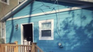 A blue house with a wooden deck and a single door.
