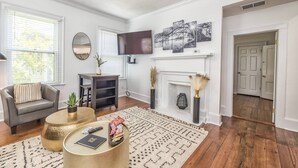 Een woonkamer met een open haard, een flatscreen televisie en een eethoek met een tafel en stoelen.