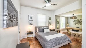 Een slaapkamer met een bed, nachtkastjes, een plafondventilator en een grote spiegel.