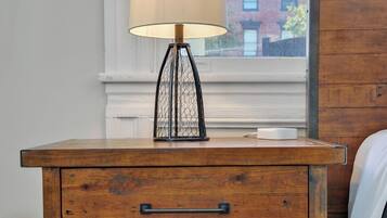 A wooden bedside table with a lamp, a drawer, and a shelf.