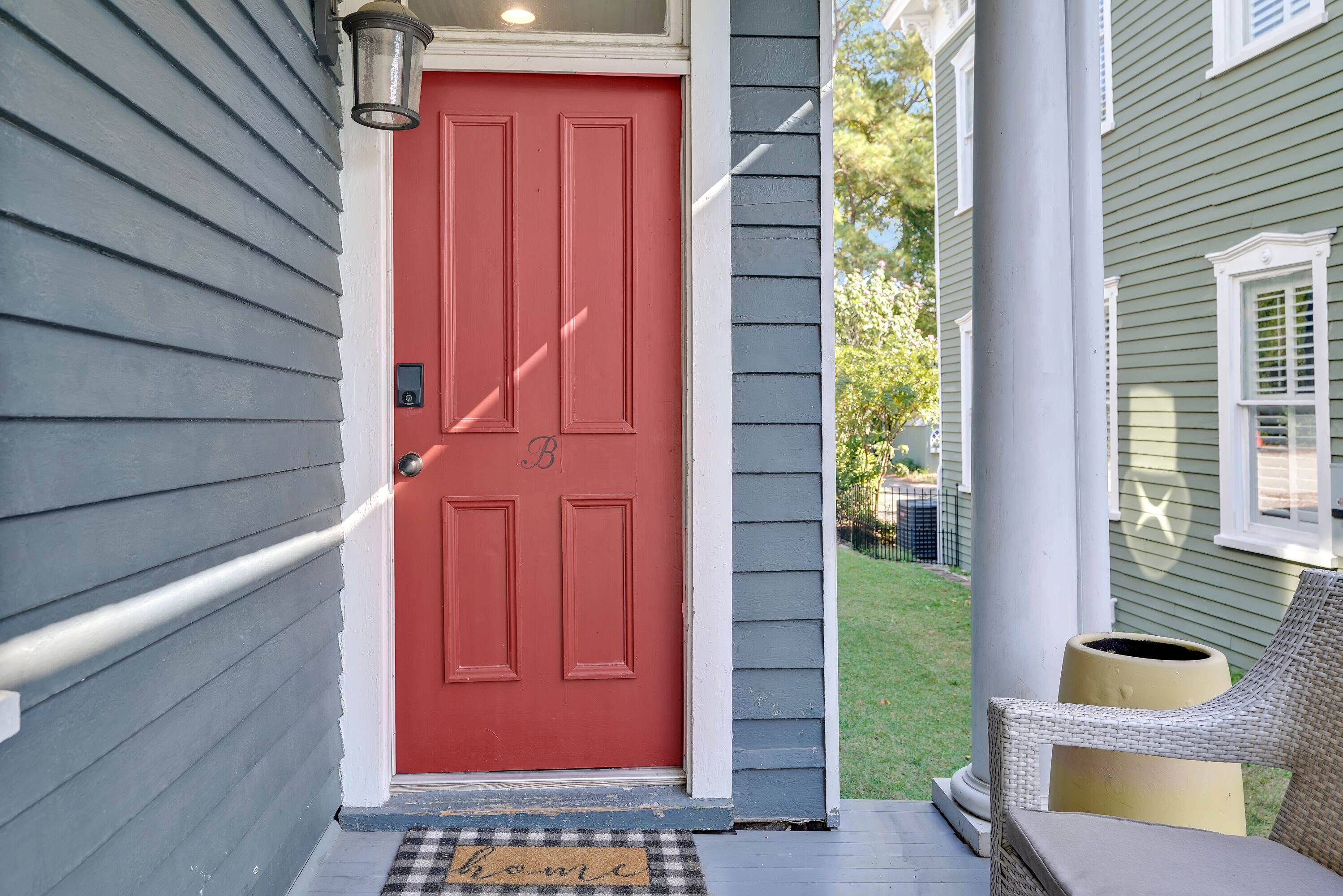 A red door with a white doorbell and a mailbox on the porch.