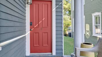 A red door with a white doorbell and a mailbox on the porch.