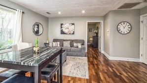 A modern living room with a dining area, featuring a marble table, grey sofa, and a large clock on the wall. - The Relaxing Zen Garden. You've found it. (Wilmington)