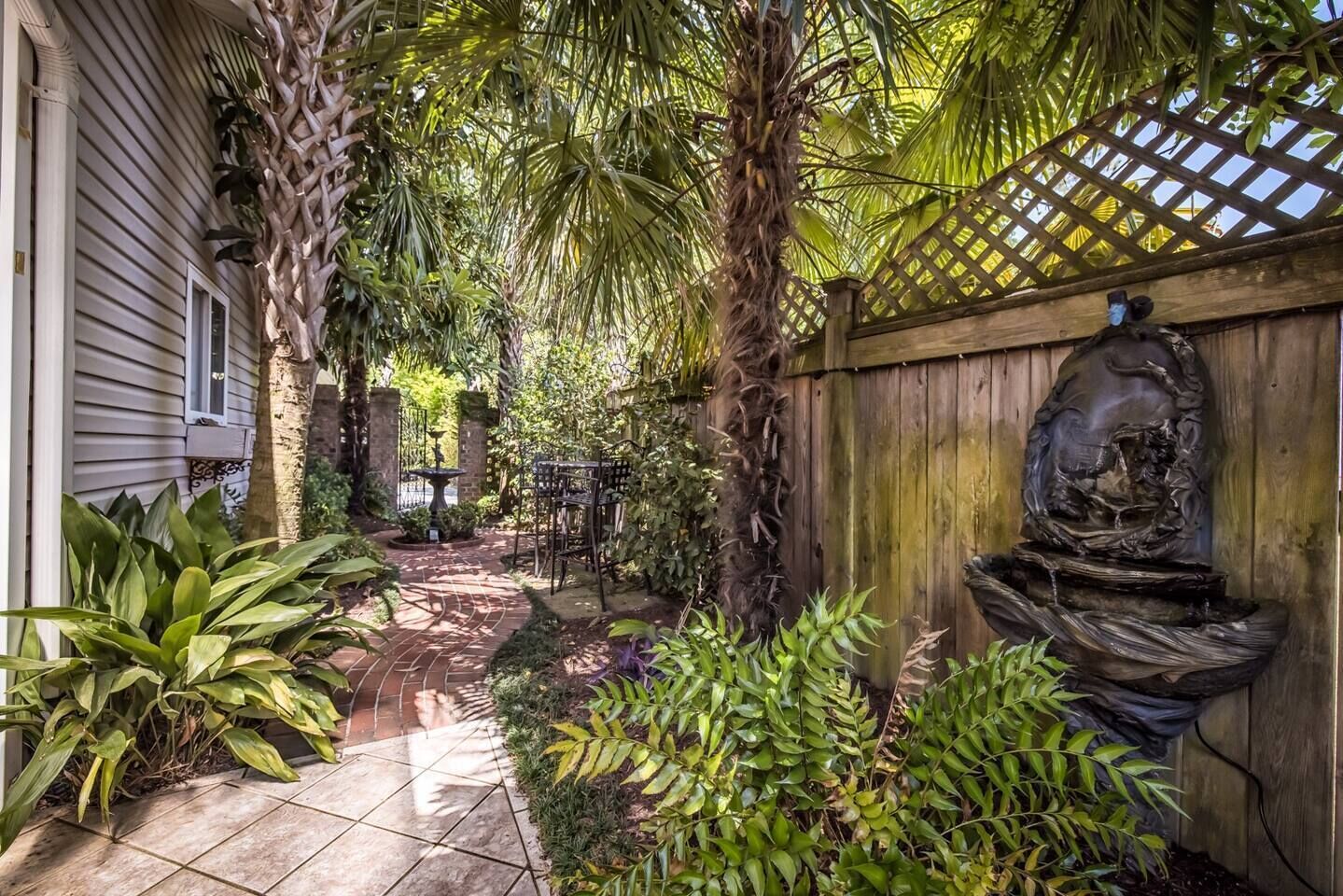 Ein Garten mit einem Brunnen, einem Holzzaun und einer gefliesten Terrasse.