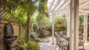 Un patio cubierto con pérgola, mobiliario exterior y una fuente decorativa.