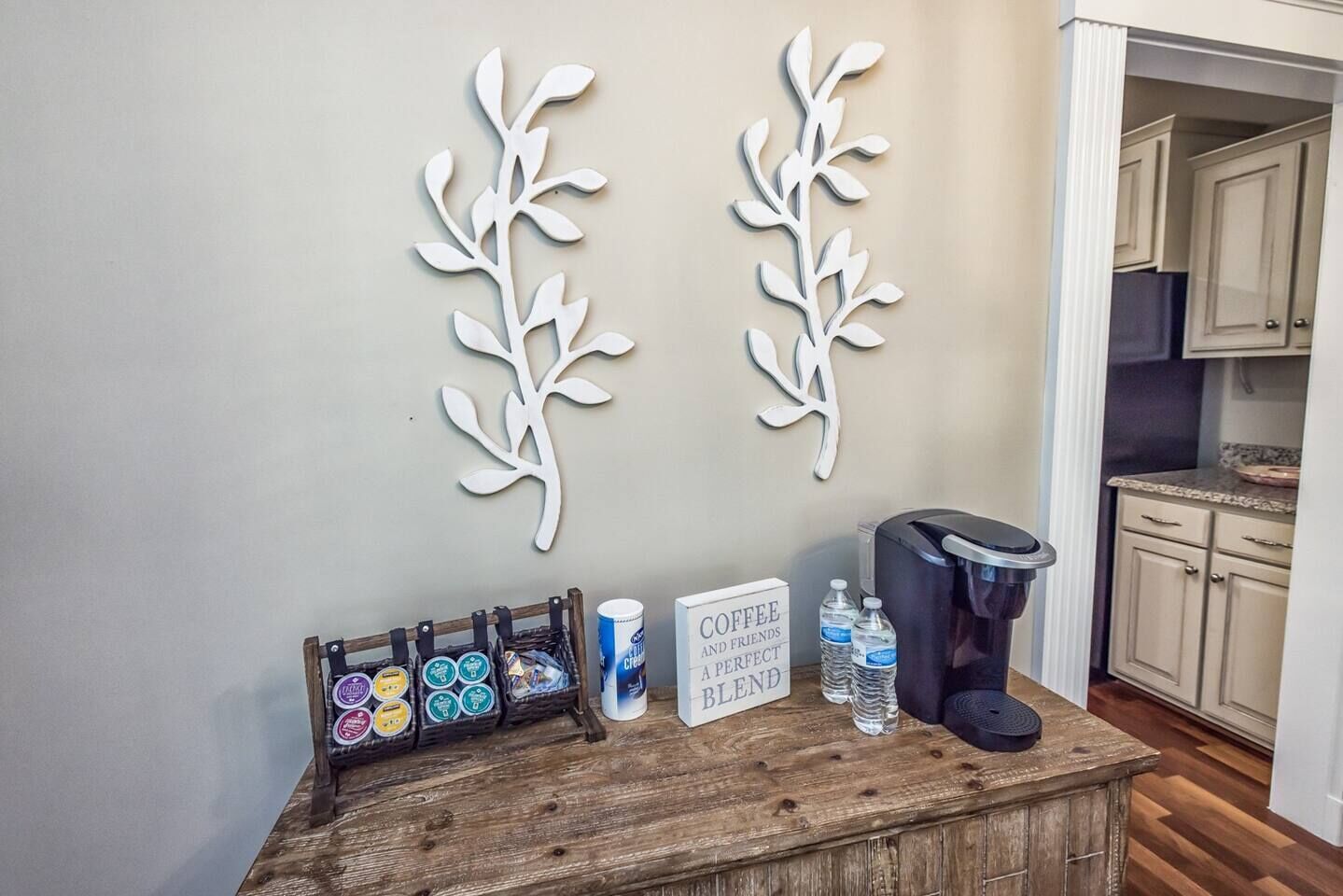 A kitchen area with a coffee station, including a coffee maker, cups, and a sign that reads "Coffee and Friends a Perfect Blend".