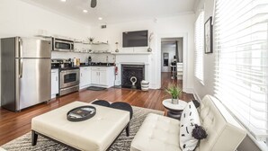 A modern kitchen with stainless steel appliances, a fireplace, and a dining area with a sofa and coffee table. - Manhattan on Front! Balcony Park Free! (Wilmington)
