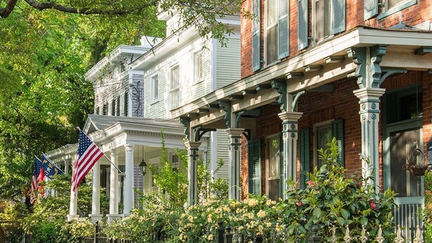 A row of historic townhouses with a covered porch, brick facade, and green shutters. - Manhattan on Front! Balcony Park Free! (Wilmington)