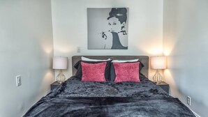 A bedroom with a bed, two bedside lamps, a headboard, and a wall-mounted artwork. - Manhattan on Front! Balcony Park Free! (Wilmington)