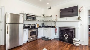 A modern kitchen with stainless steel appliances, white cabinetry, a fireplace, and a flat-screen TV. - Manhattan on Front! Balcony Park Free! (Wilmington)