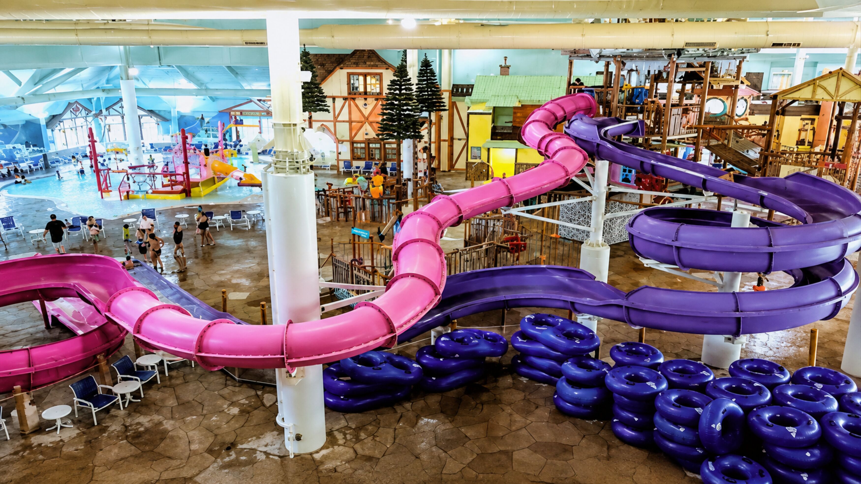 Parque acuático interior con múltiples toboganes y anillos inflables.