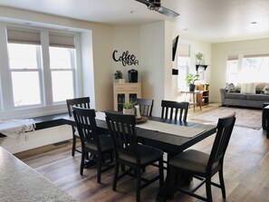 A dining area with a black table and chairs, a coffee bar sign, and a view of the living room. - Luxury on Main, remodeled, homey, fresh and bright! (Bozeman)