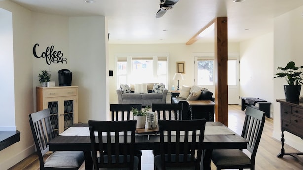 Una cocina moderna con comedor, que cuenta con una encimera de mármol, sillas de madera y un letrero que dice 'Coffee Bar' en la pared.