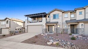 A modern two-story house with a covered patio, a stone facade, and a well-maintained gravel driveway. - The Legacy Retreat Near National Parks! (Hurricane)