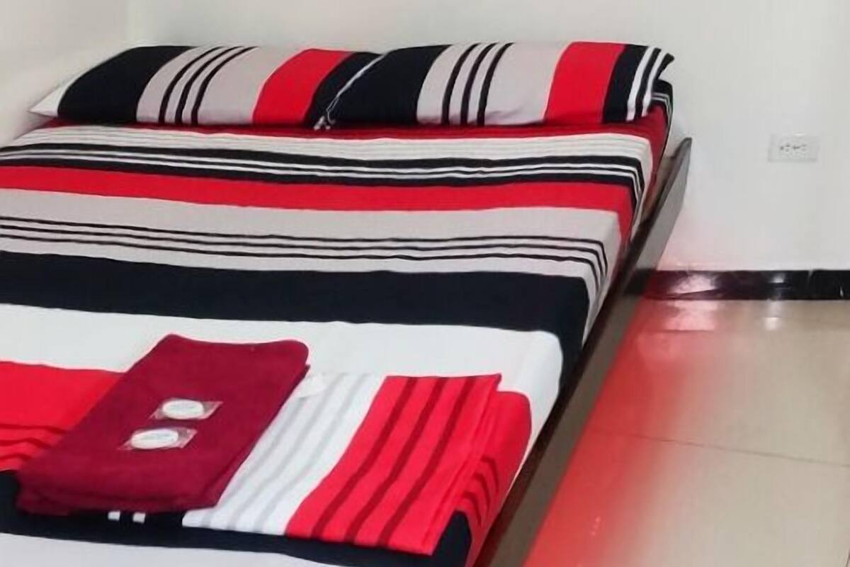 A bedroom with a bed, pillows, and a nightstand.