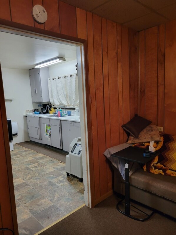 Habitación compacta con kitchenette, un pequeño sofá y una mesa.