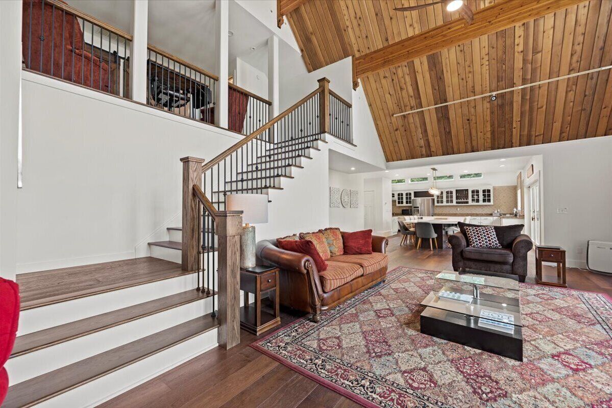 A spacious living area with a wooden staircase, a leather sofa, and a coffee table.