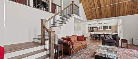 A spacious living area with a wooden staircase, a leather sofa, and a coffee table.
