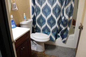 Bathroom features a toilet, sink, and shower, with a cabinet and tiled floor.