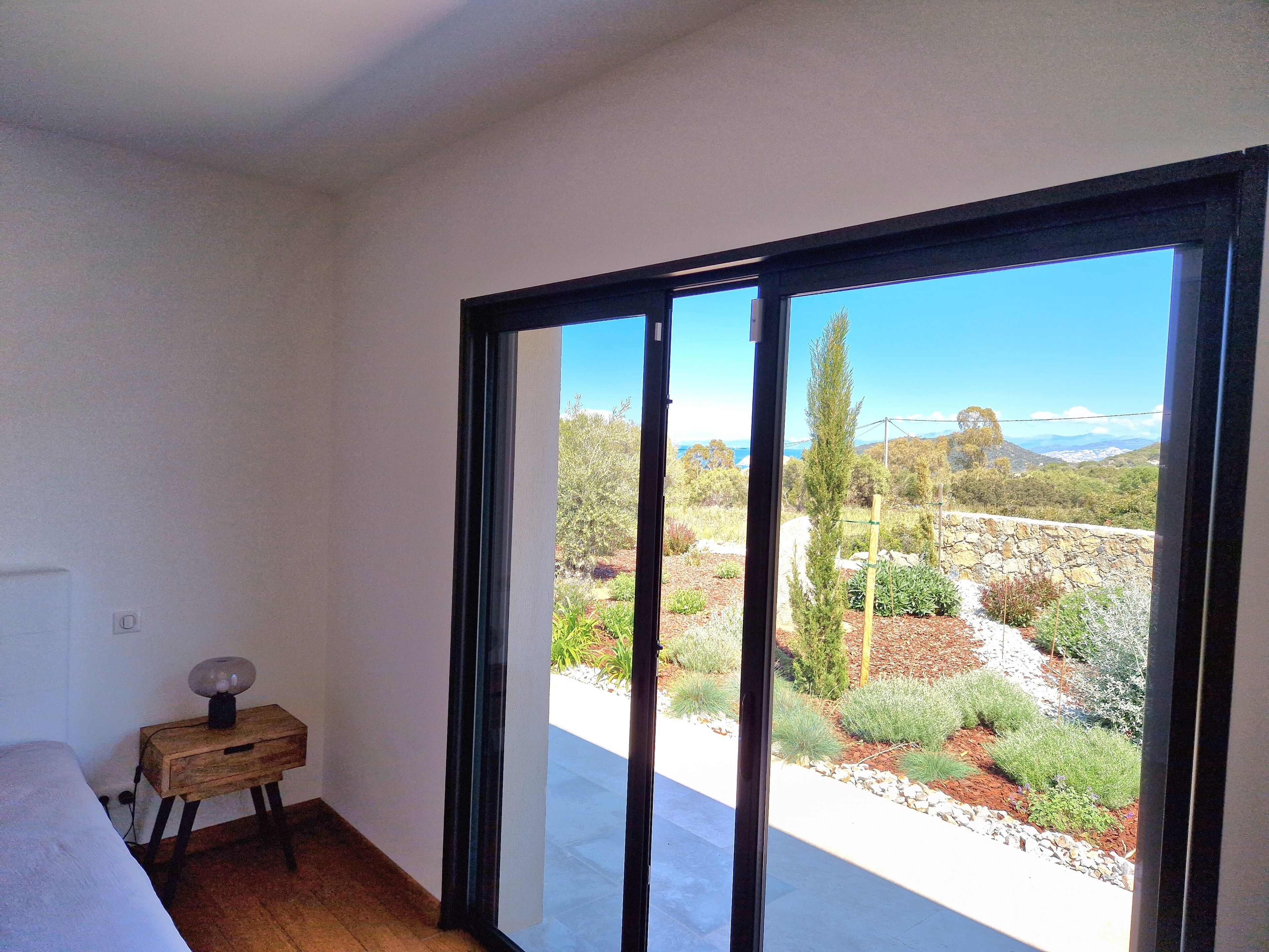 A bedroom with a large sliding glass door leading to a garden.