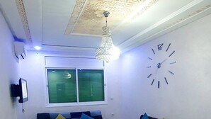 Un salon avec un canapé, une table basse, un téléviseur et une horloge murale.