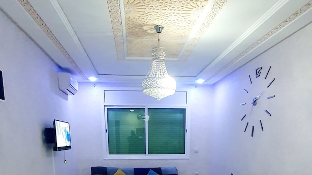 Un salon comprenant un ensemble de canapés, une table basse, un téléviseur fixé au mur et un plafond décoratif.