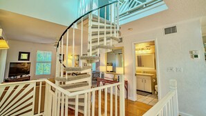 Ein mehrstöckiges Wohnhaus mit Wendeltreppe, einem Wohnzimmer mit Fernseher, einer Küche und einem Badezimmer.