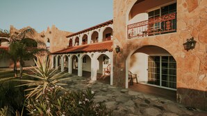 Ein Innenhof mit Steinbögen, einem roten Ziegeldach und einem Balkon mit schmiedeeisernen Geländern.