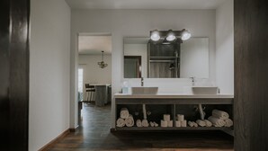 Ein modernes Badezimmer mit zwei Waschbecken, einem großen Spiegel und einem Handtuchhalter.