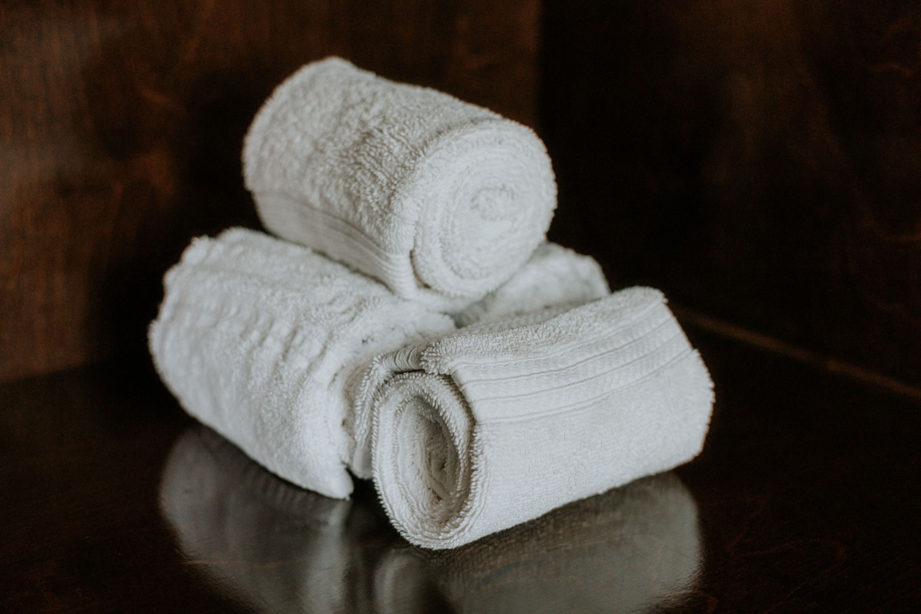 A stack of white towels on a reflective surface.