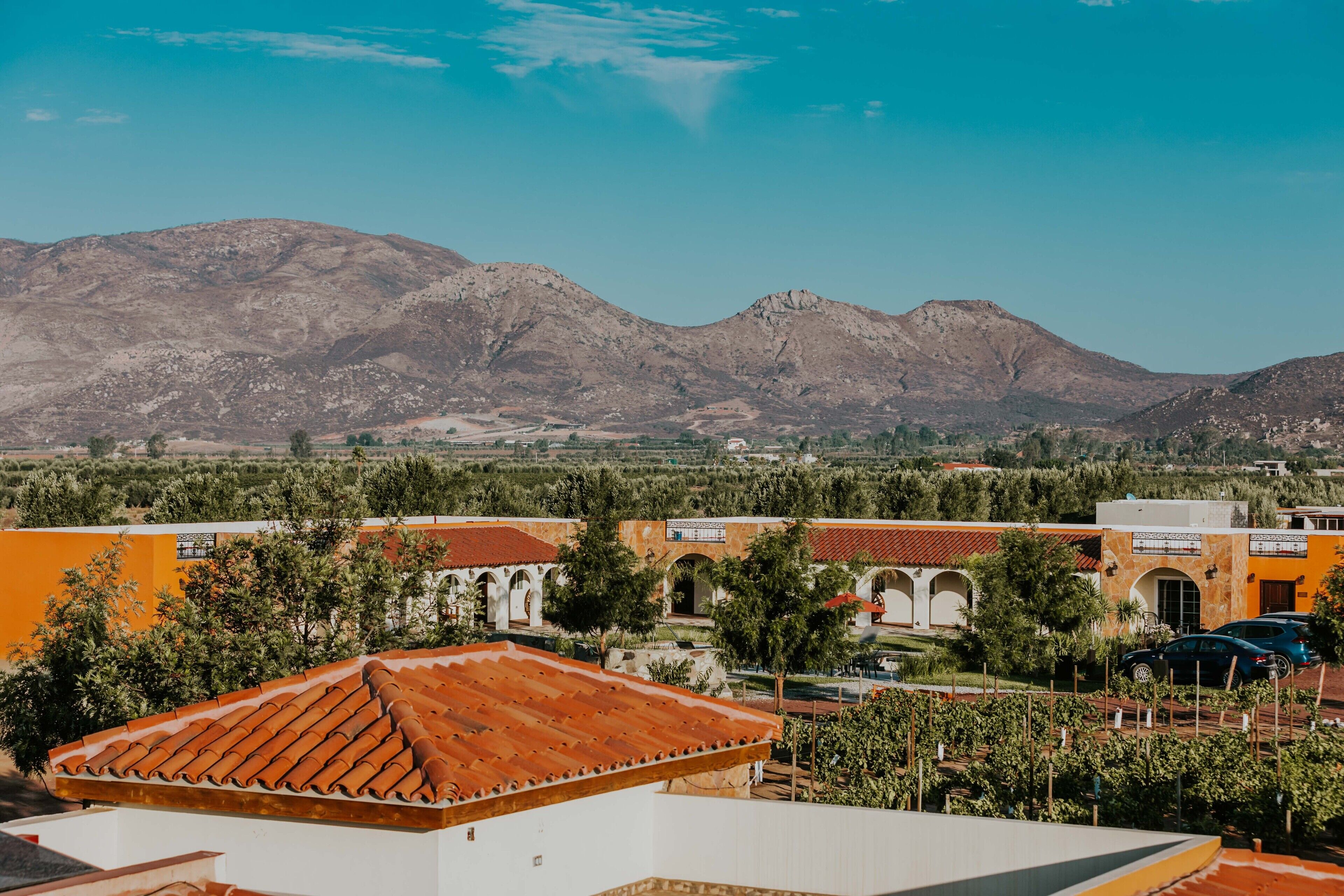 A view of a mountainous landscape with buildings in the foreground, including a structure with a red-tiled roof.