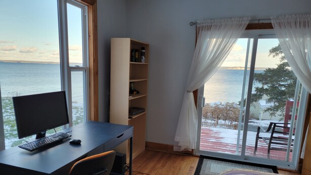 Un dormitorio con escritorio, computadora y vista al mar.