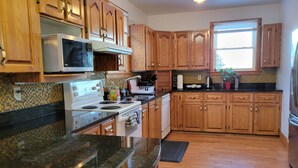 Una cocina con armarios de madera, estufa, microondas y ventana.