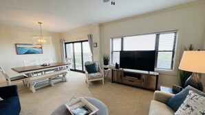 A living room with a dining area, a TV, and a large window.