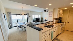 A modern kitchen with a central island, a dining area with a view, and a ceiling fan.