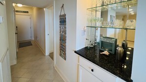 A kitchen with a glass display case containing wine glasses and a sign that reads "I always take a little piece of the beach home with me."