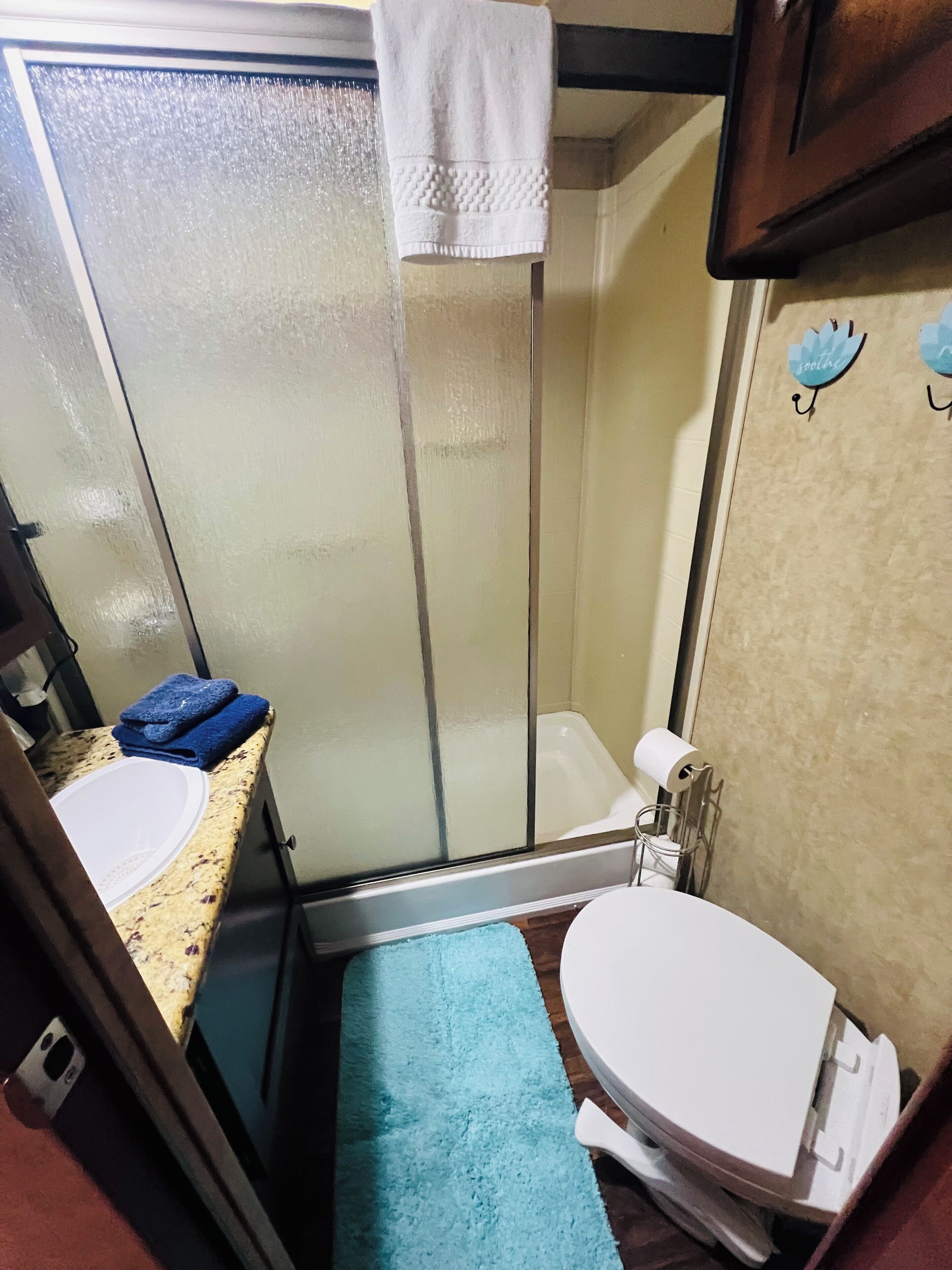 A compact bathroom with a shower, toilet, and sink.