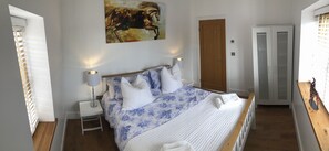 Cozy retreat with a large bed, nightstand, and wardrobe, featuring a beautiful painting above.