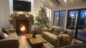 A cozy living room with a fireplace, a Christmas tree, and a sofa. - Modern Converted Stables in the heart of Pembrokeshire (Wiston)