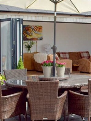 Relax in a serene outdoor space with a round table, wicker chairs, and lush greenery.