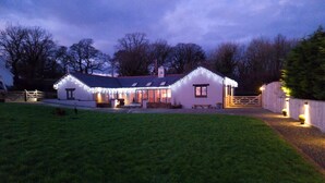 A house with a sloped roof, a front porch, and a fenced yard. - Modern Converted Stables in the heart of Pembrokeshire (Wiston)