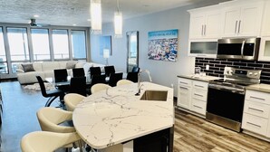Una cocina moderna con armarios blancos, una isla de mármol y electrodomésticos de acero inoxidable.