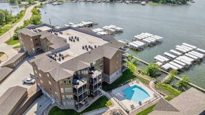 Un hotel de varios pisos con piscina en la azotea, un puerto deportivo con barcos y una vista panorámica al frente marítimo.