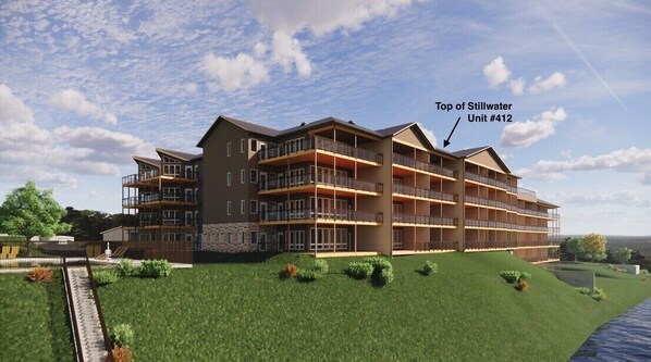 A multi-story hotel with balconies, a landscaped lawn, and a view of the water. - Top of Stillwater by Okoboji Luxury Rentals (Arnolds Park)