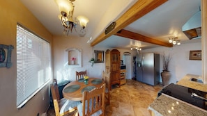 A spacious kitchen with a dining area, wooden beams, a built-in stove, and a refrigerator.