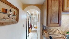 A hallway with a framed painting, a wooden cabinet, and a shower area.